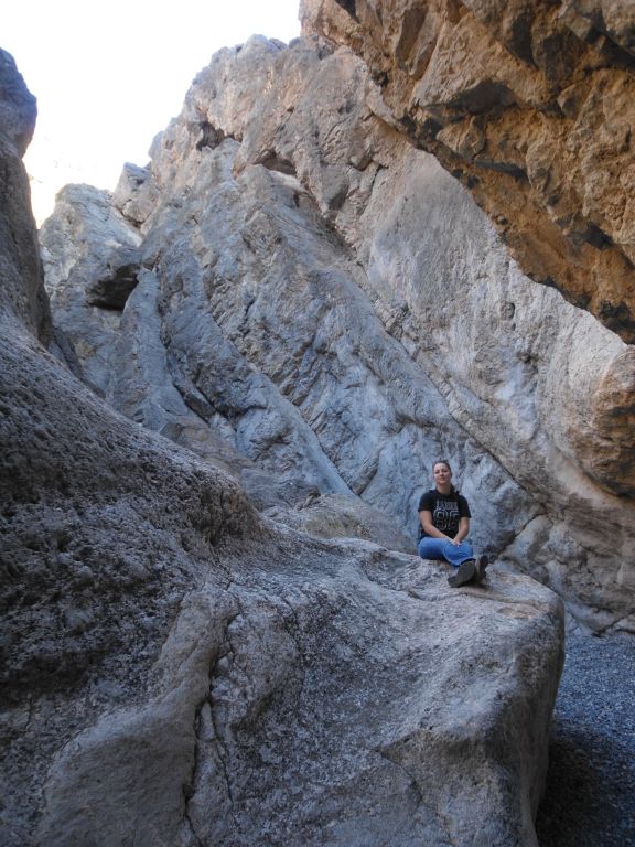 Tiffany getting her picture on a rock while the other side of the canyon wall hangs over her head: