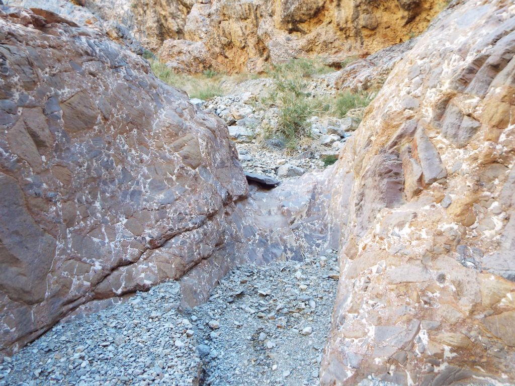 A small dry fall with a large boulder made up of similar rocks on each side of it: