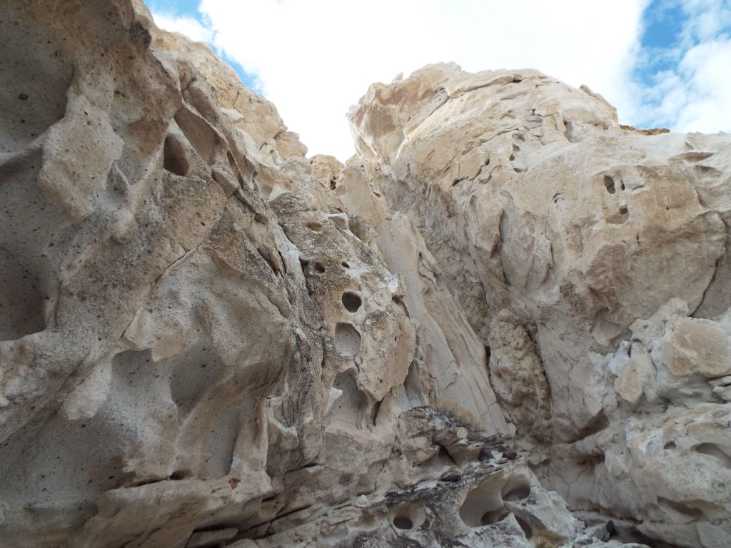 A visually beautiful contrast between the high slot canyon walls of white and the white clouds with patches of blue sky above: