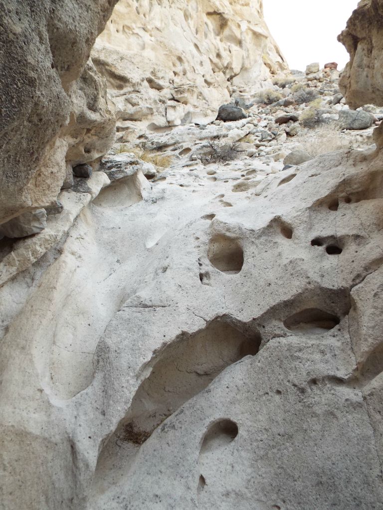 A polished dry fall with a groove cut into the rock with tafoni formations next to it: